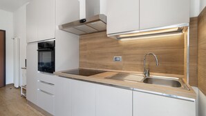 Een moderne keuken met witte kasten, roestvrijstalen apparatuur en een houten spatwand.