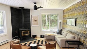 Ein gemütliches Wohnzimmer mit Kamin, einer Couch, einem Couchtisch und einer Wand mit Muster.