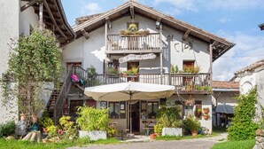 Ein traditionelles Gebäude mit Balkon, Außenbestuhlung und Blumentöpfen.