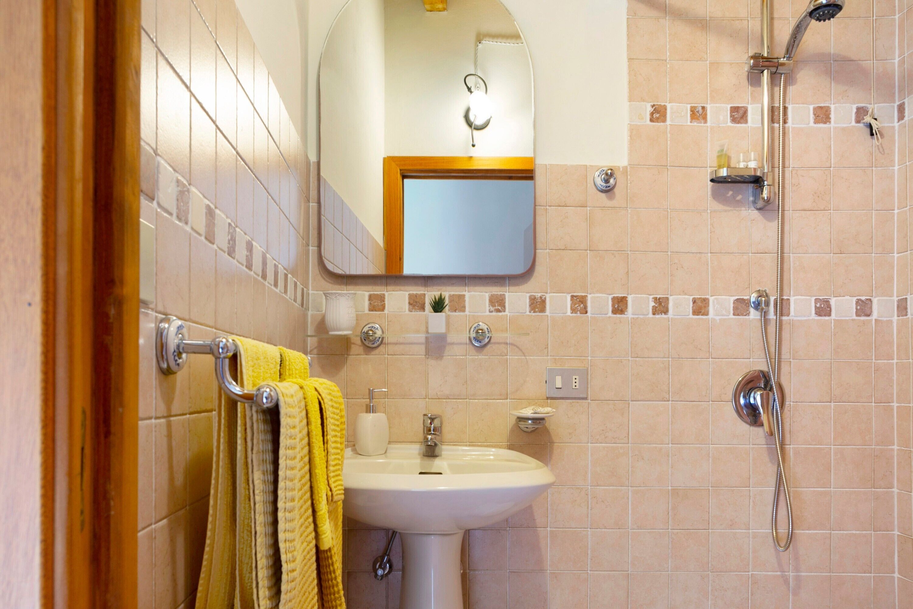 A bathroom with a sink, mirror, towel rack, and shower.