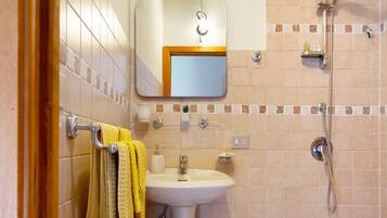 A bathroom with a sink, mirror, towel rack, and shower.