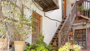 Ein rustikales Gebäude mit einer Holztreppe, Topfpflanzen und einem Balkon mit Geländern.