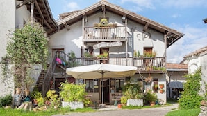 A traditional building with a balcony, outdoor seating, and potted plants. - Room 'Camera 2' with Mountain View, Shared Garden and Wi-Fi (Arsiè)
