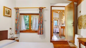 A bedroom with a bed, a window with curtains, a bedside table with a lamp, and a wooden ceiling. - Room 'Camera 2' with Mountain View, Shared Garden and Wi-Fi (Arsiè)