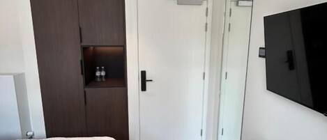 A bedroom with a bed, a wardrobe, a TV, and a mirror.