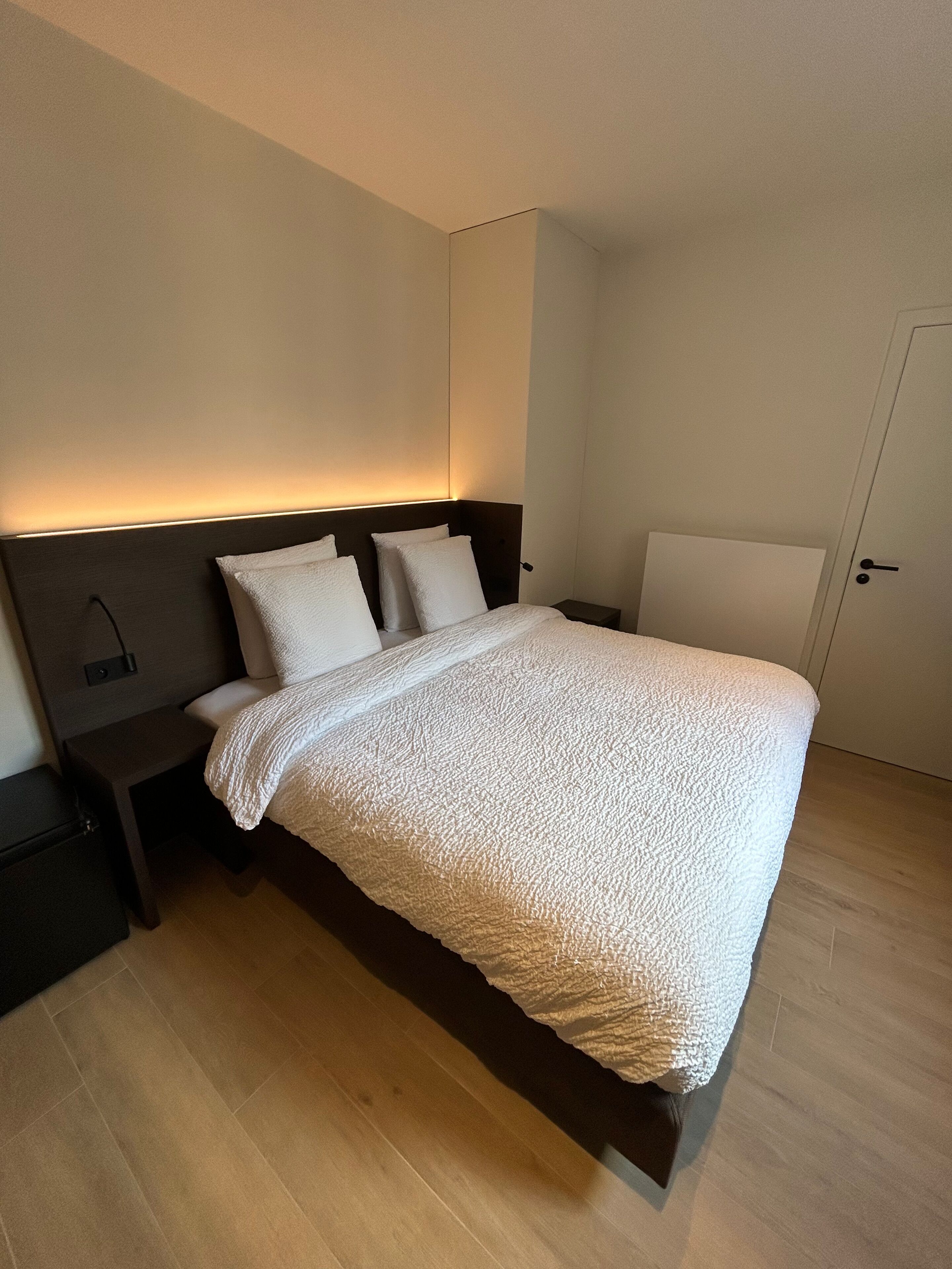 A modern bedroom with a large bed, a bedside table, and a nightstand.