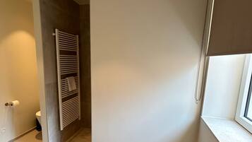 A bathroom with a toilet, towel rack, and a window with a blind.