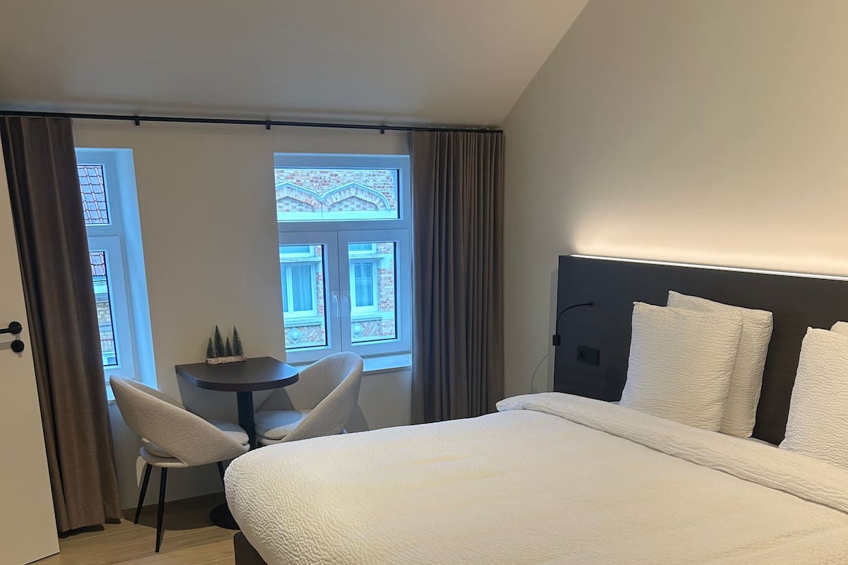 A modern hotel room with a large bed, a small table, and a chair.