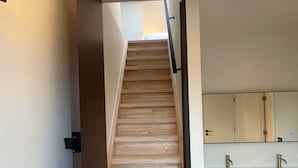 A staircase leading to a bathroom with a wooden finish and a modern design. - Manteka Logies (Ypres)