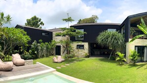 Uma casa moderna com piscina, paredes de pedra e vegetação exuberante.