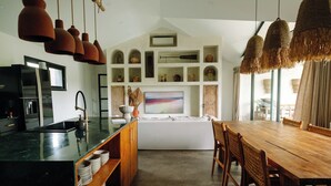 Cozinha moderna com bancada preta, armários de madeira e área de jantar com mesa e cadeiras de madeira.