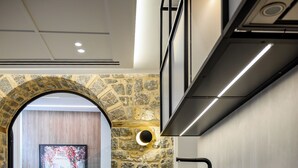 A modern kitchen with a stone archway leading to a living area, featuring a large framed picture and a sofa.
