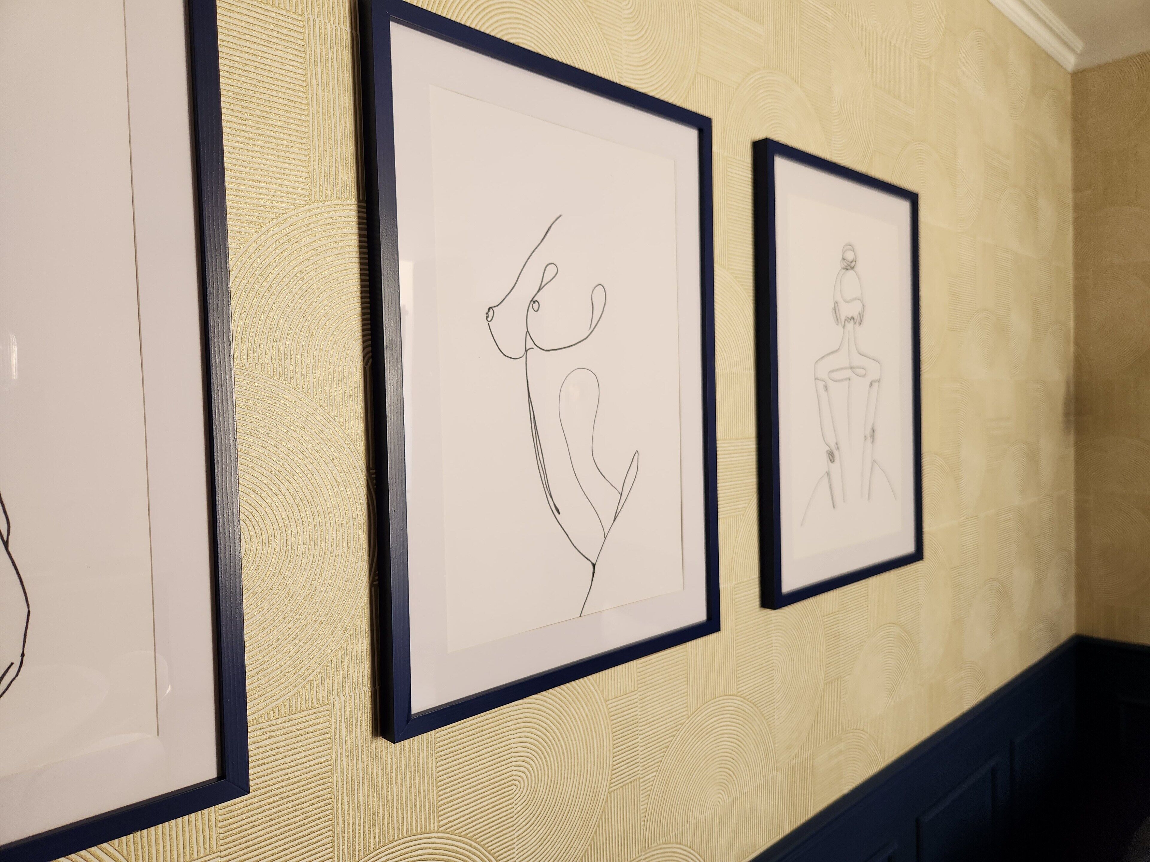 Three framed line drawings on a textured wall.