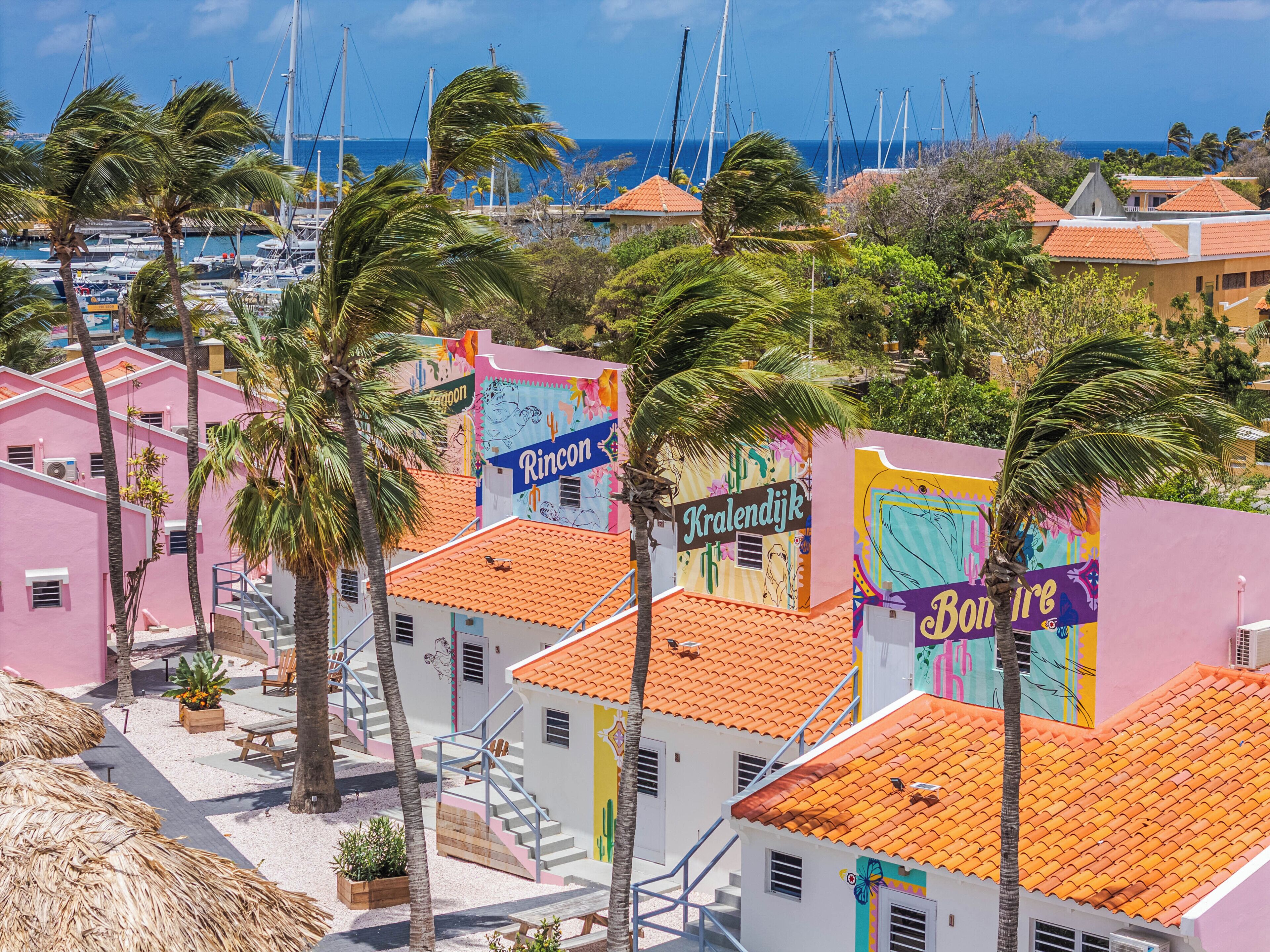 A coastal area with colorful buildings, a marina, and palm trees.