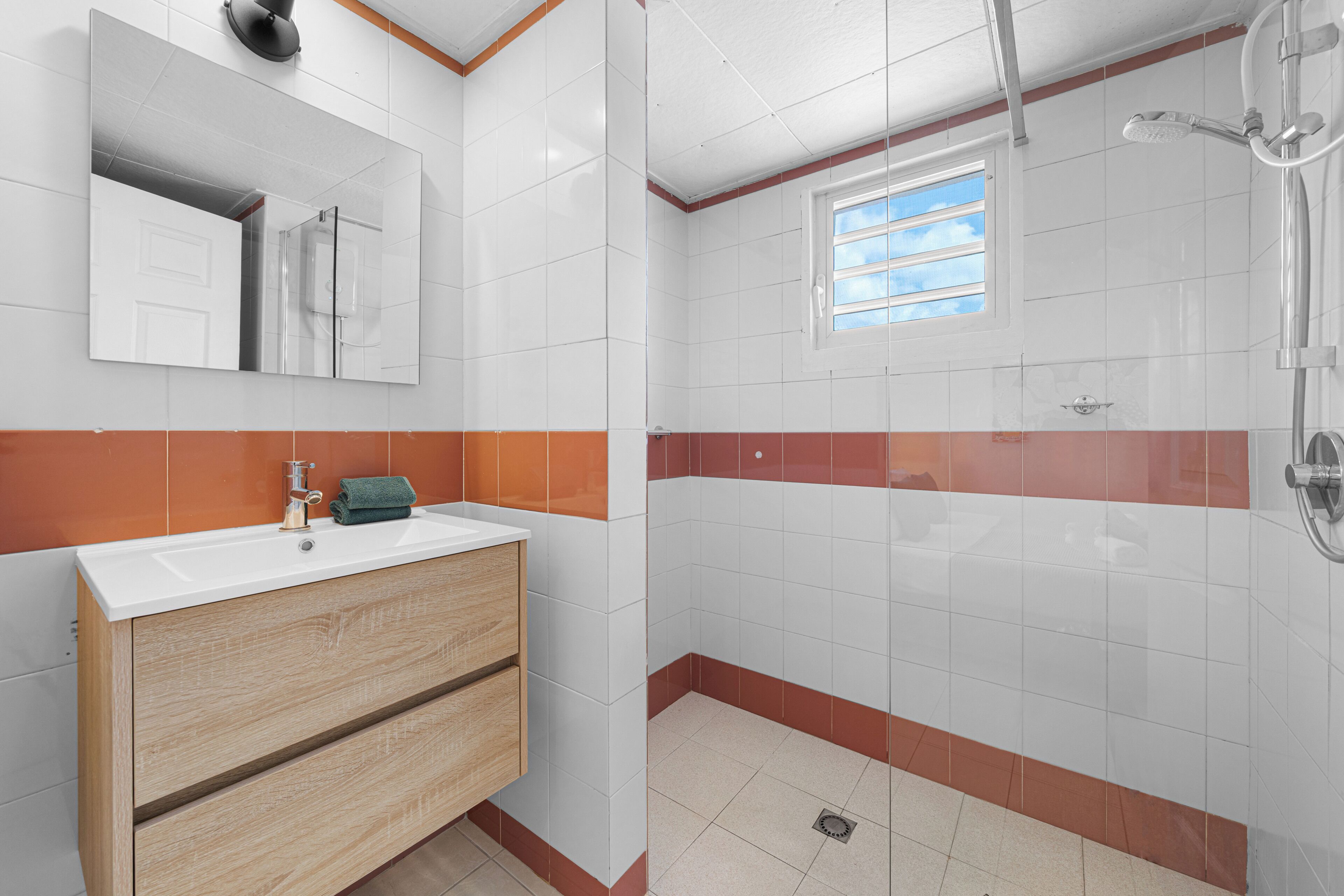 Un baño con lavamanos, espejo y ducha.