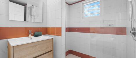 Un baño con lavamanos, espejo y ducha.