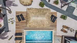 An aerial view of a rooftop pool area with a wooden deck, lounge chairs, and a central pool. - Pink Lagoon by Boutique Bonaire Unique Resorts (Kralendijk)