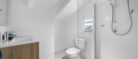 A modern bathroom with a shower, toilet, and sink.