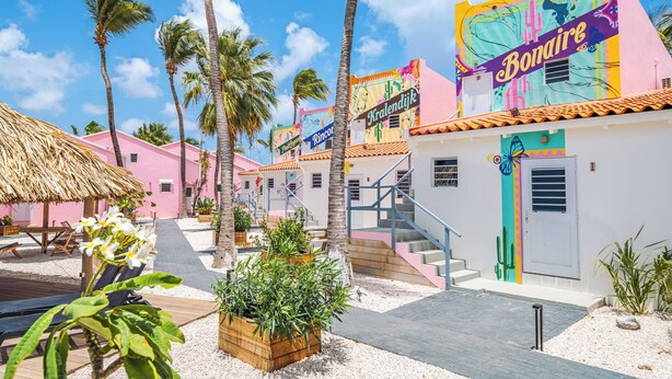 A colorful building with a staircase and a thatched-roof structure. - Pink Lagoon by Boutique Bonaire Unique Resorts (Kralendijk)