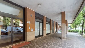 Un pasillo cubierto con suelo de piedra, puertas de cristal y un letrero que indica una ubicación.