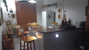 Eine Küche mit Bar, weißen Backsteinwänden und einer Holztür.