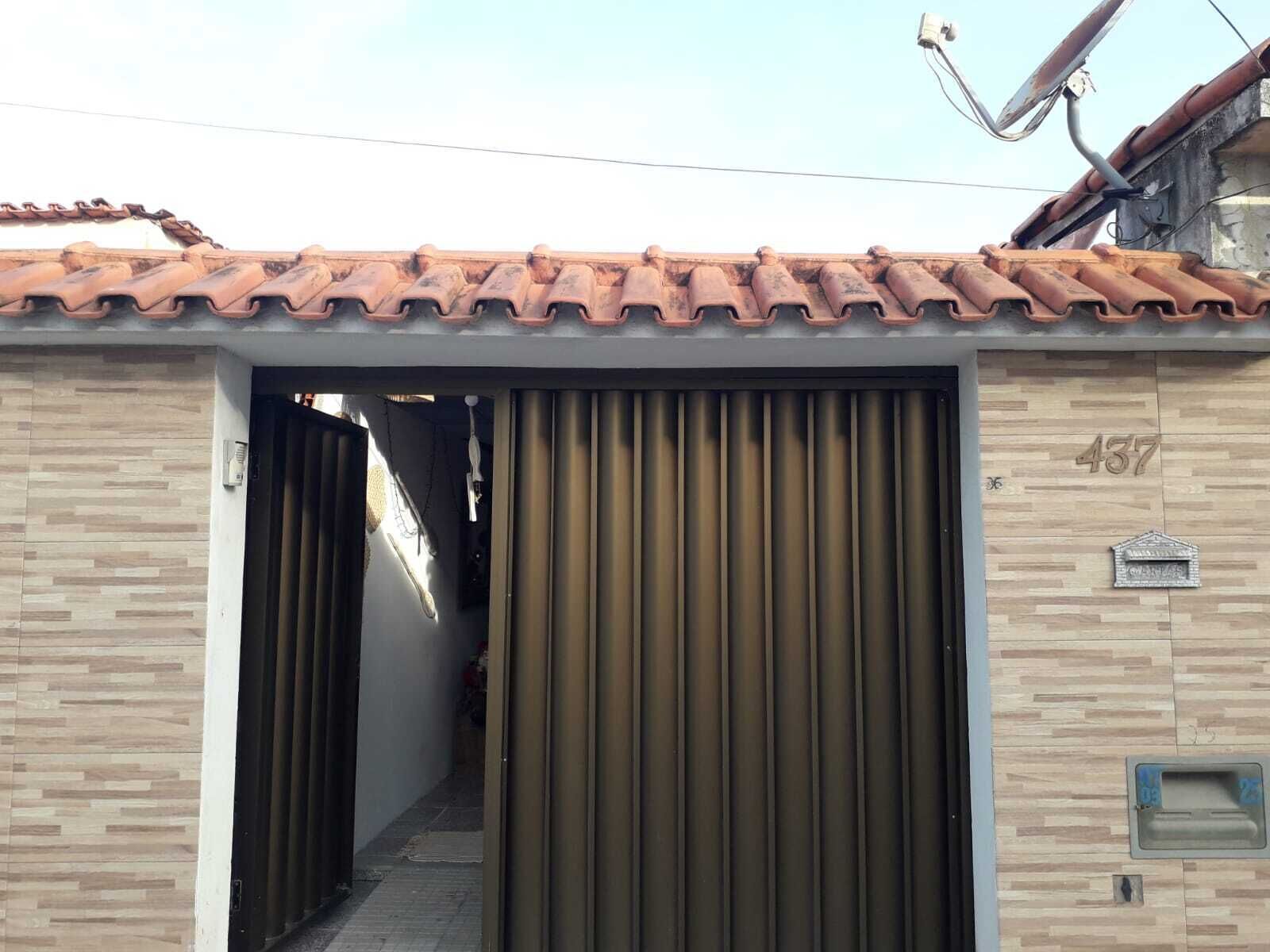A building with a tiled roof, a large metal gate, and a mailbox.