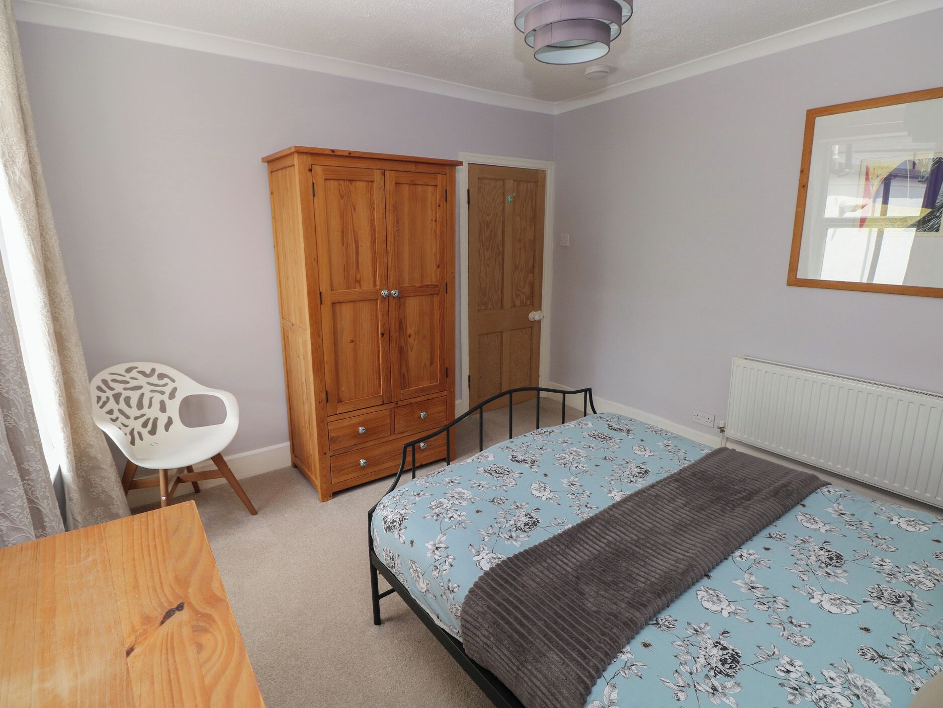A bedroom with a bed, a wardrobe, a chair, and a radiator.