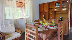 A dining area with wooden furniture, a table set with plates, glasses, and fruit. - | White cabin | Fireplace, fireplace, tranquility, ideal for families and friends (Gonçalves)