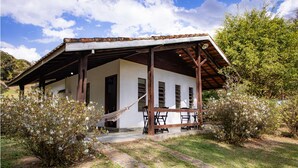 Un edificio rústico con un porche de madera, una hamaca y un sendero de piedra que lleva a la entrada.