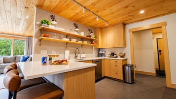 Una cocina moderna con armarios de madera, una isla central y un comedor con sillas de cuero.