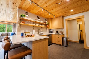 Una cocina moderna con armarios de madera, una isla central y un comedor con sillas de cuero.