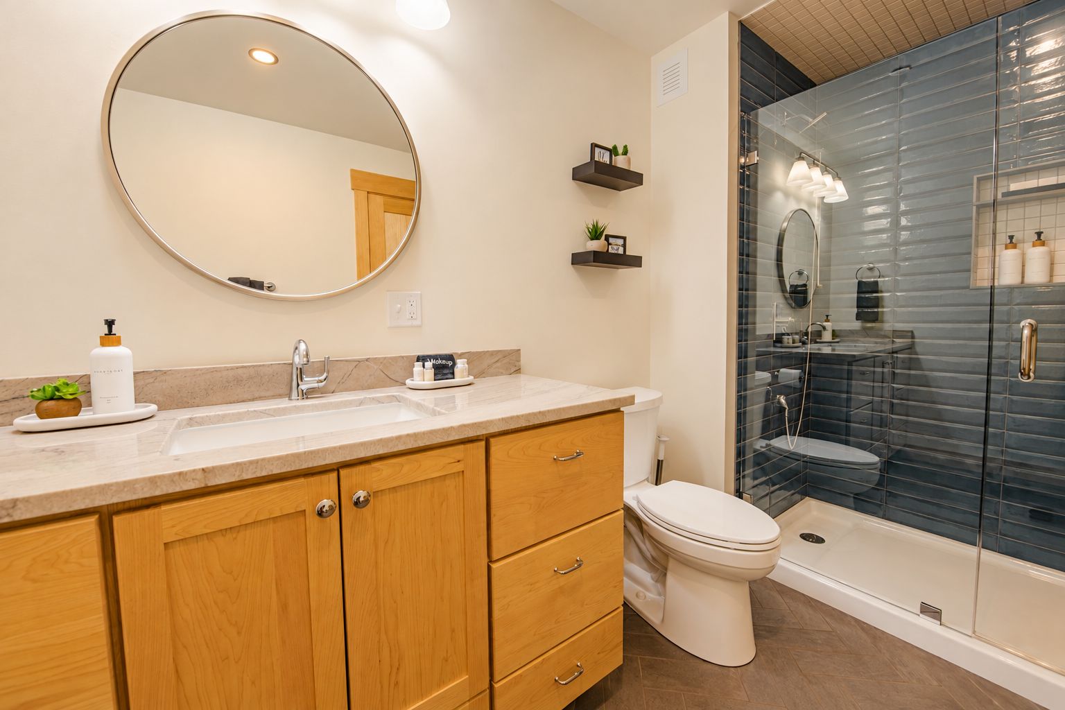 Une salle de bain avec un meuble-lavabo à deux vasques, des toilettes et une douche séparée par une paroi en verre.
