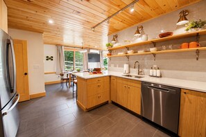 Una cocina moderna con armarios de madera, lavavajillas de acero inoxidable y ventana con vista a un jardín.