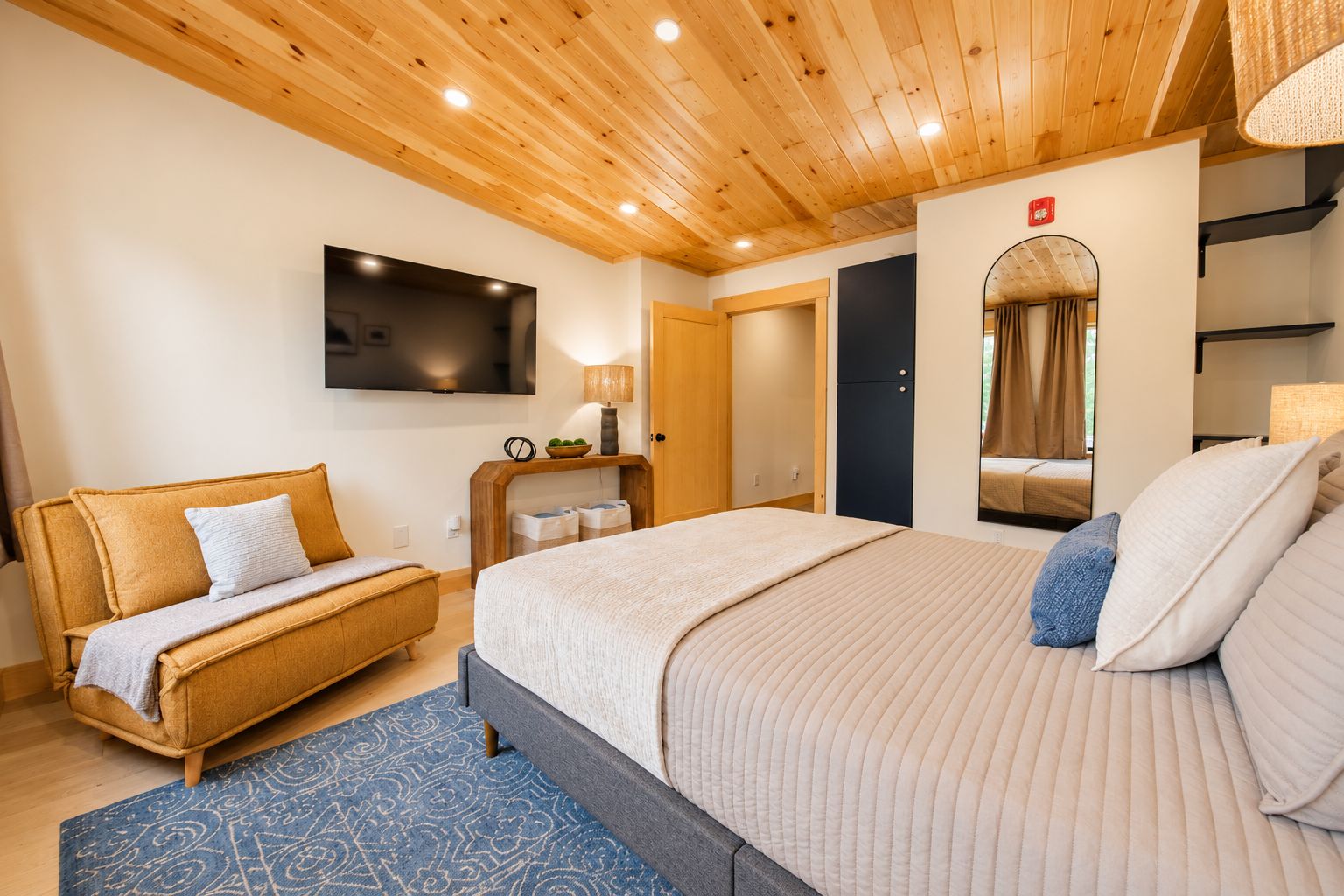 Ein Hotelzimmer mit Bett, Sofa, Fernseher, Spiegel und Holzboden.
