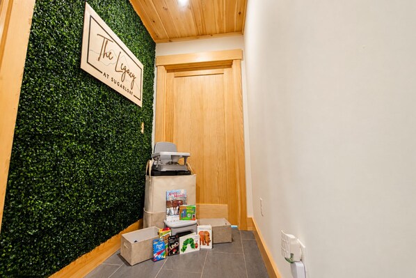 Un pasillo con pared verde, puerta de madera y un contenedor de basura.
