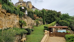 A garden with a stone wall, a wooden bench, and a gazebo. - CHAMBRE D'HÖTE AT THE FOOT OF THE CHATEAU SLIDING-SCALE RATES PLUS 2 NIGHTS WEEKEND INCLUDED (Castelnaud-la-Chapelle)
