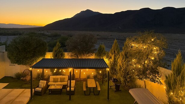 A patio with outdoor furniture, string lights, and a view of mountains. - Departamentos Aremay (Cuatro Ciénegas)