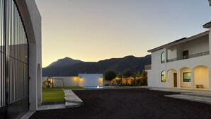 A modern building with a pool, outdoor seating, and a mountain backdrop. - Departamentos Aremay (Cuatro Ciénegas)
