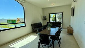 A modern room with a dining table, chairs, a sofa, and a TV. - Departamentos Aremay (Cuatro Ciénegas)