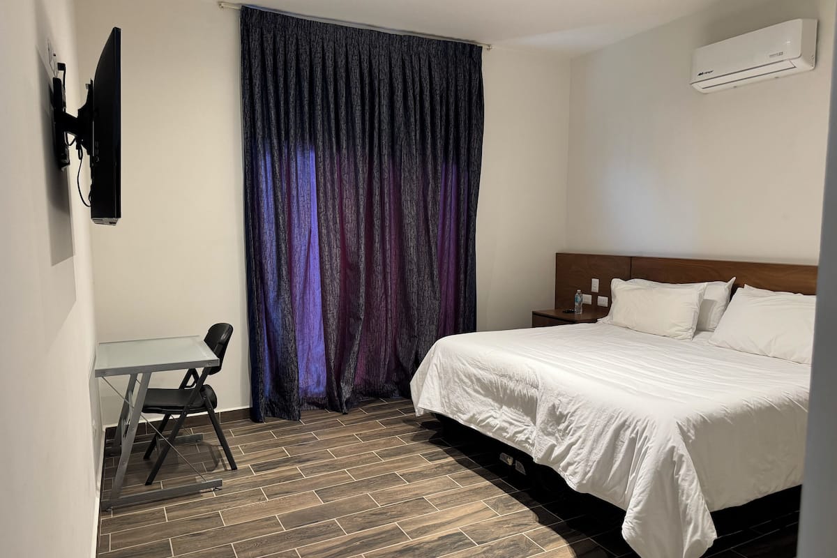 Een hotelkamer met een bed, een bureau, een stoel en een gordijn.