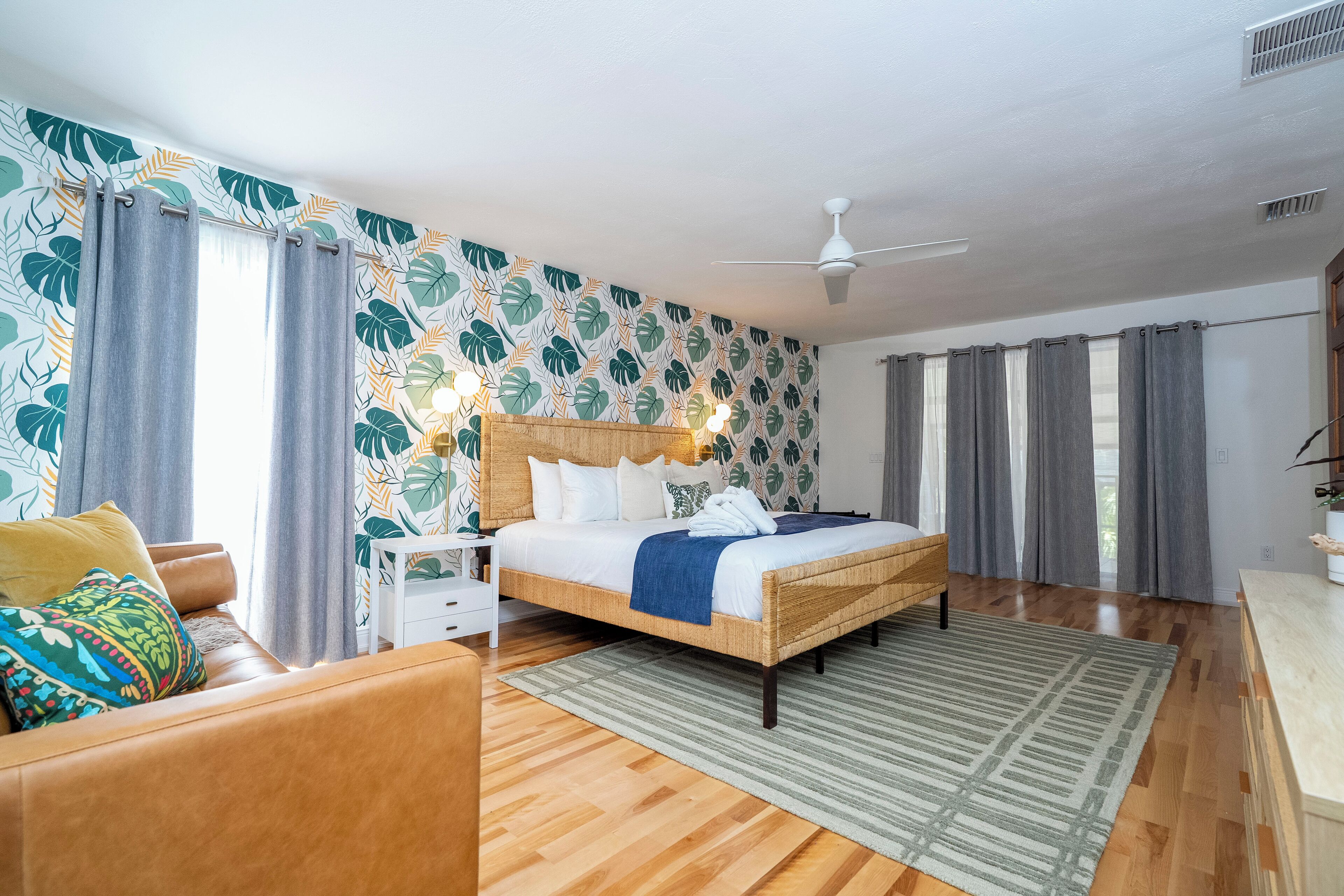 Un dormitorio con cama, mesita de noche, sofá y ventilador de techo.