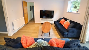 Ein Wohnzimmer mit Fernseher, zwei Sofas, einem Couchtisch und einem Fenster.