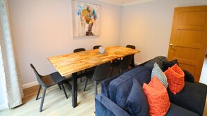 Ein Essbereich mit einem Holztisch, schwarzen Stühlen und einem blauen Sofa mit gemusterten Kissen.