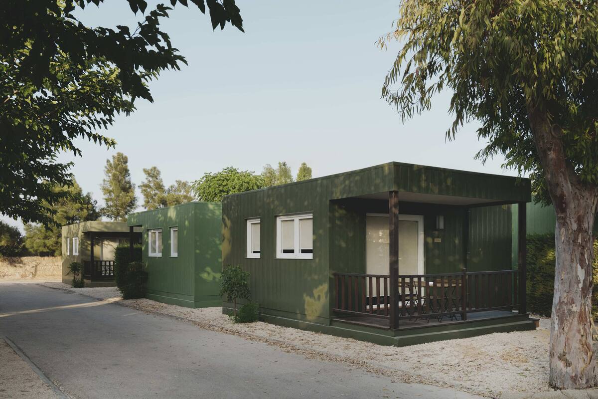 A green single-story building with a porch, windows, and a door.