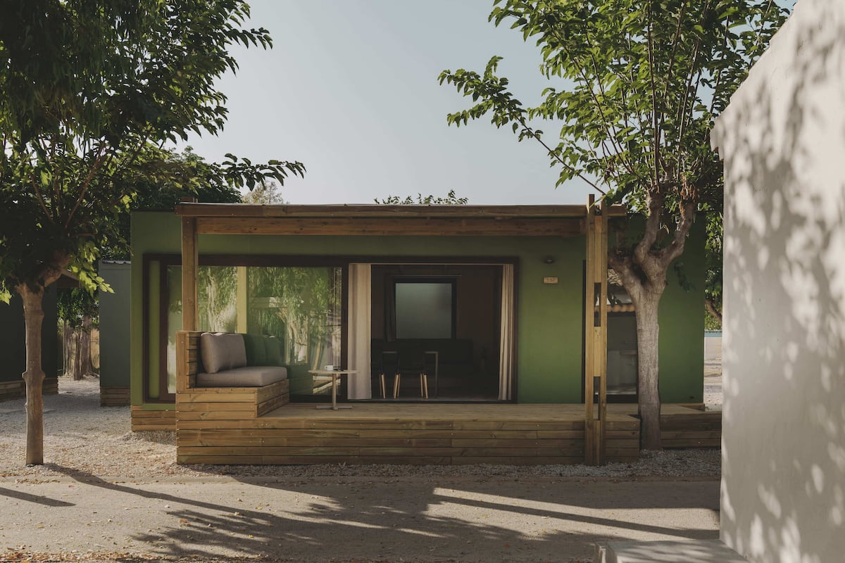 A modern outdoor living space with a wooden deck, a sofa, and a television.