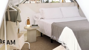 A tented room with a bed, a small table with a lamp, and a hanging bag labeled "CREAM". - wecamp Jávea (Javea)
