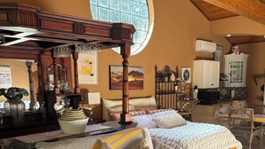 Ein gemütliches Schlafzimmer mit einem großen Bett, einer Couch, einer Holzbalkendecke und einem großen Fenster.