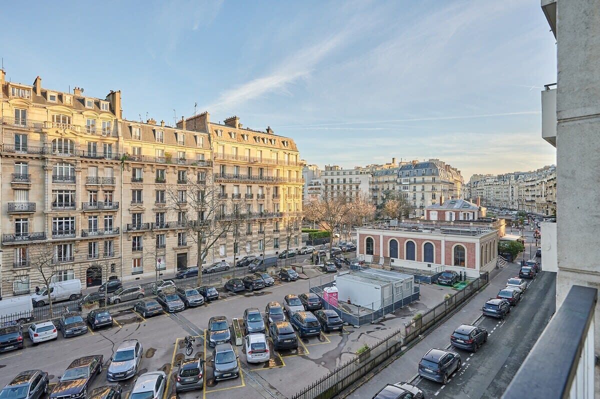 A parking lot with multiple cars and a building with a red facade in the background.