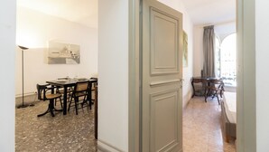 A room with a dining area featuring a table and chairs, a bed, and a window with curtains. - Rental in Rome Angelico Apartment (Rome)