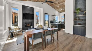 A modern living room with a fireplace, dining area, and kitchen. - Mountain Views Eden Cabin w/ Hot Tub & Fireplace (Eden)